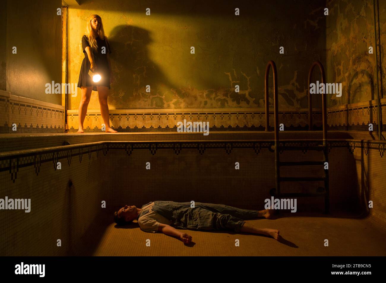 Un giovane uomo sembra giacere morto in una piscina vuota come una giovane donna guarda; Lincoln, Nebraska, Stati Uniti d'America Foto Stock