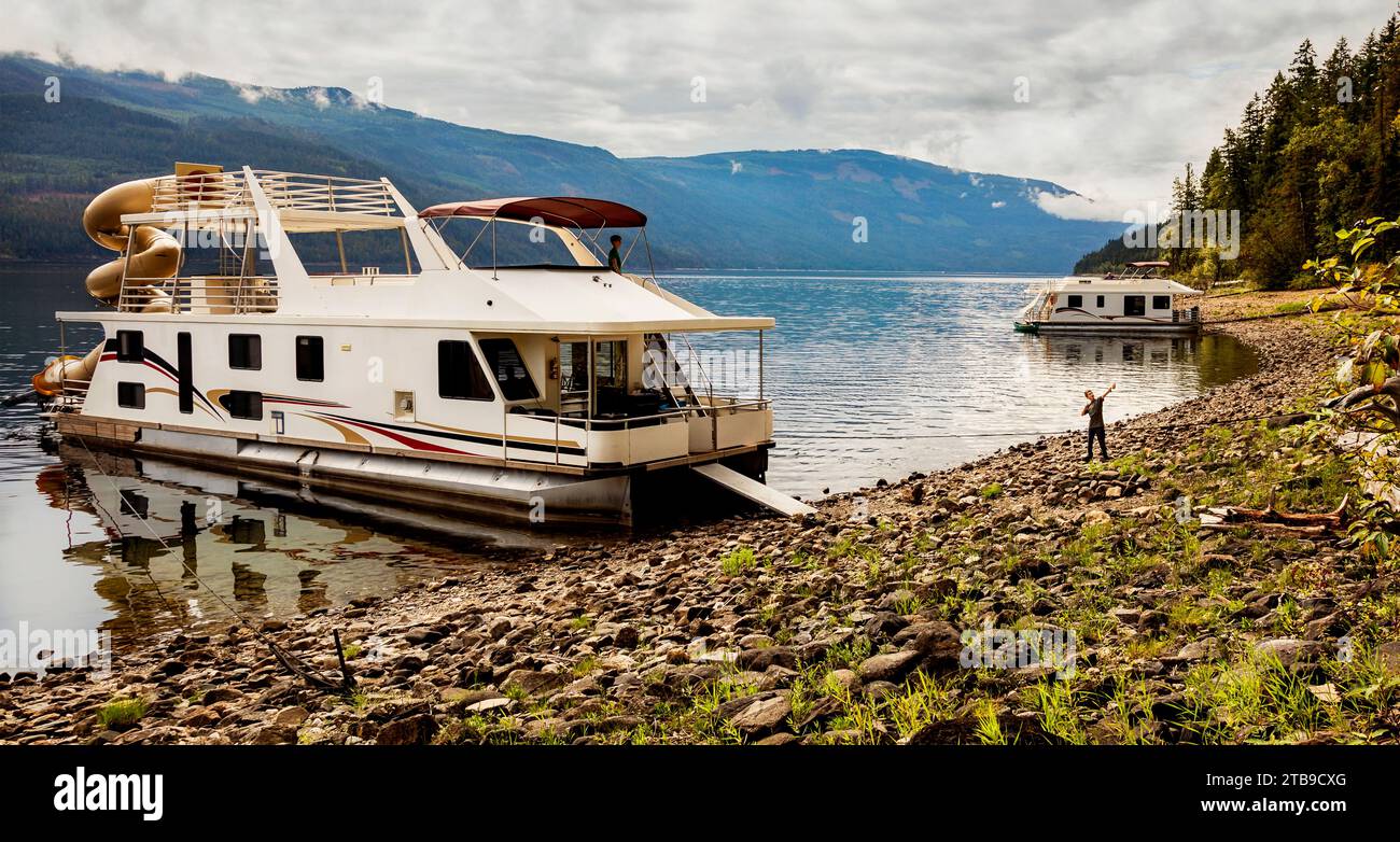 Una famiglia che si gode una vacanza in casa galleggiante mentre è parcheggiata sulla riva del lago Shuswap; lago Shuswap, British Columbia, Canada Foto Stock