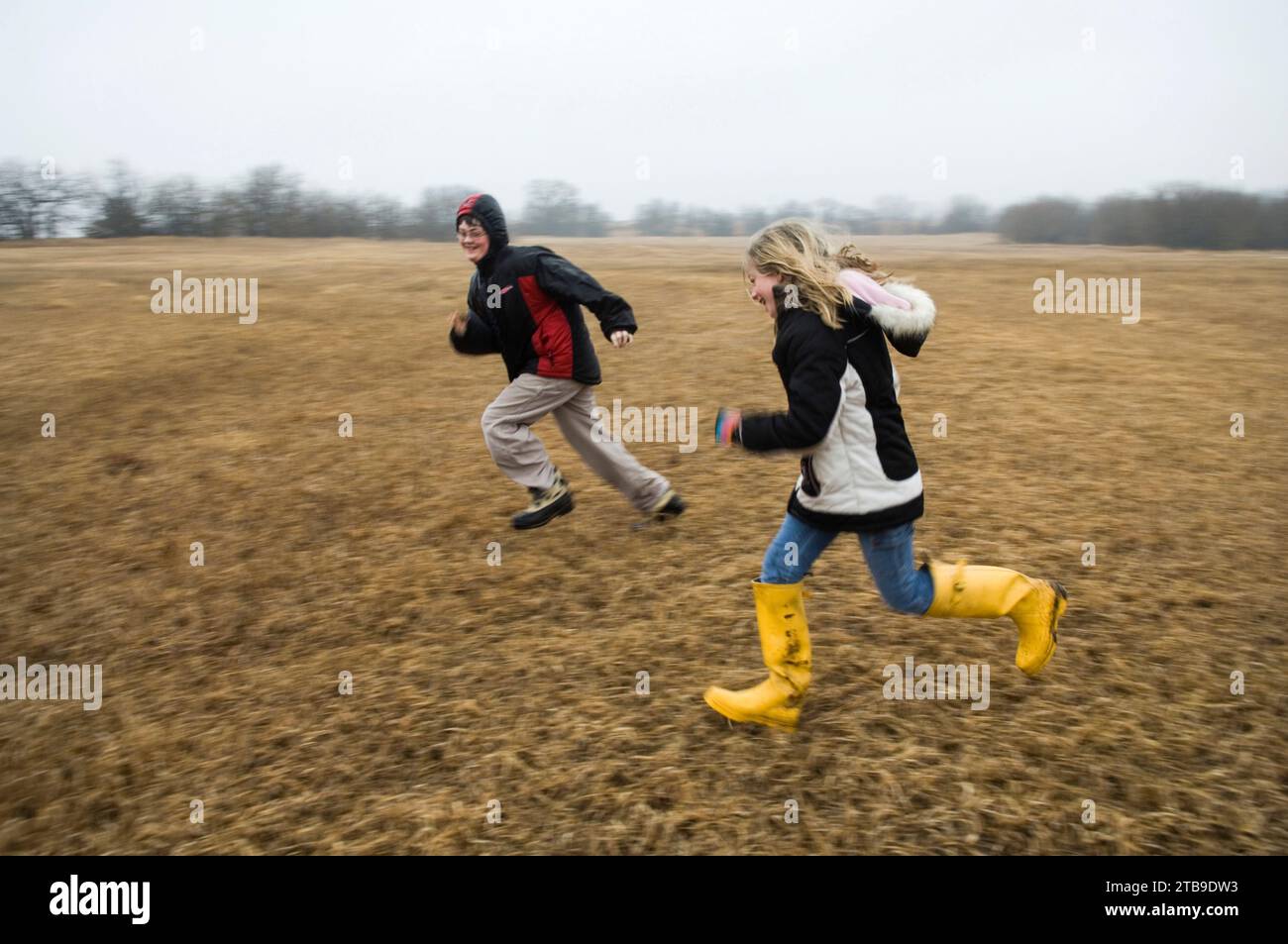 Ragazzo e ragazza corrono e si inseguono in un campo; Lincoln, Nebraska, Stati Uniti d'America. Foto Stock