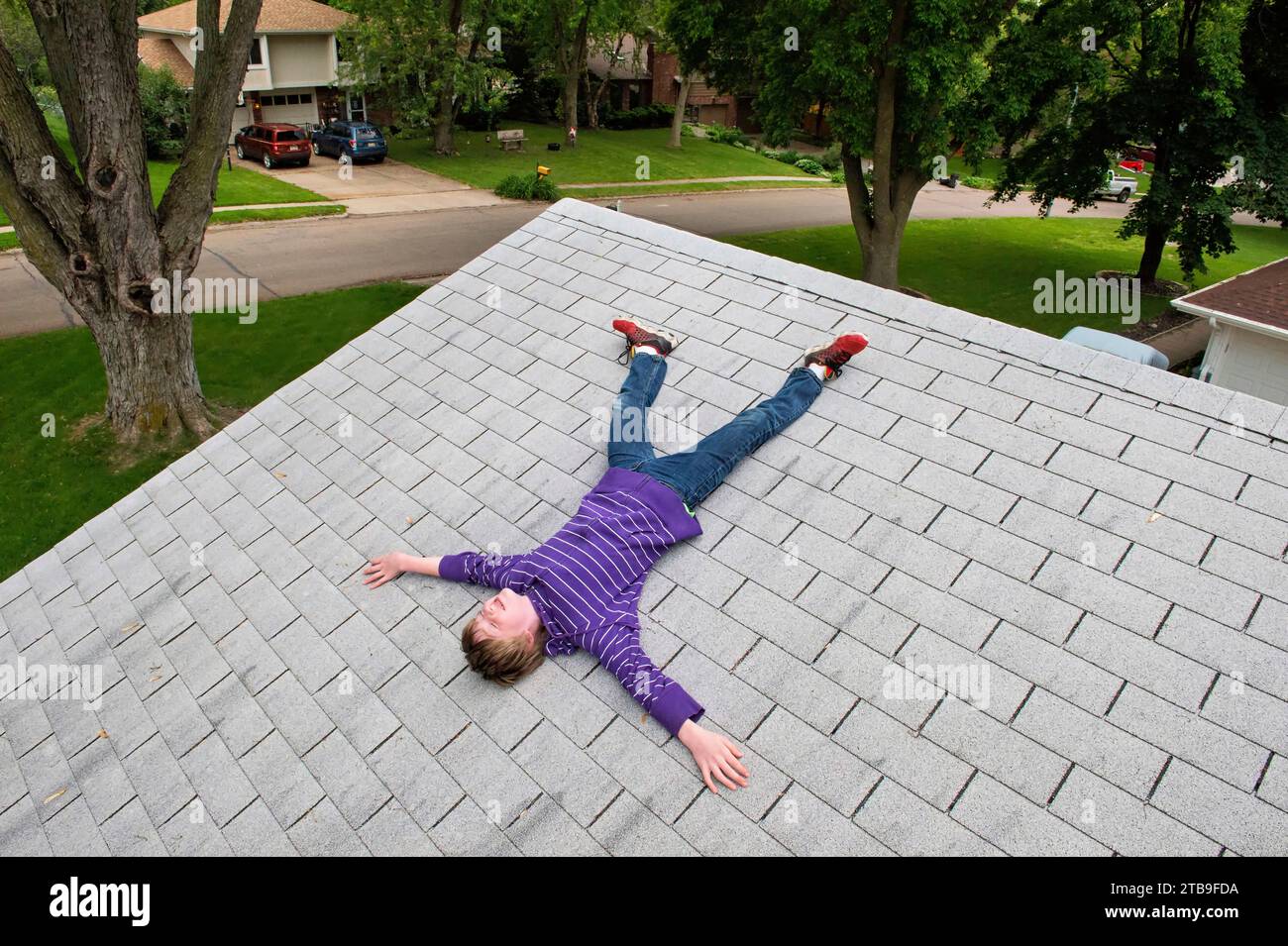 Ragazzo di età elementare che si trova sul tetto di una casa, Elkhorn, Nebraska, Stati Uniti d'America Foto Stock