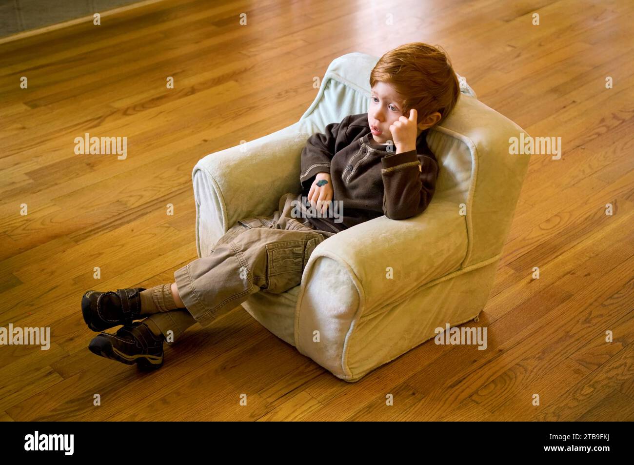 Bambino in età prescolare guarda la TV nella sua poltrona da bambino; Atlanta, Georgia, Stati Uniti d'America Foto Stock