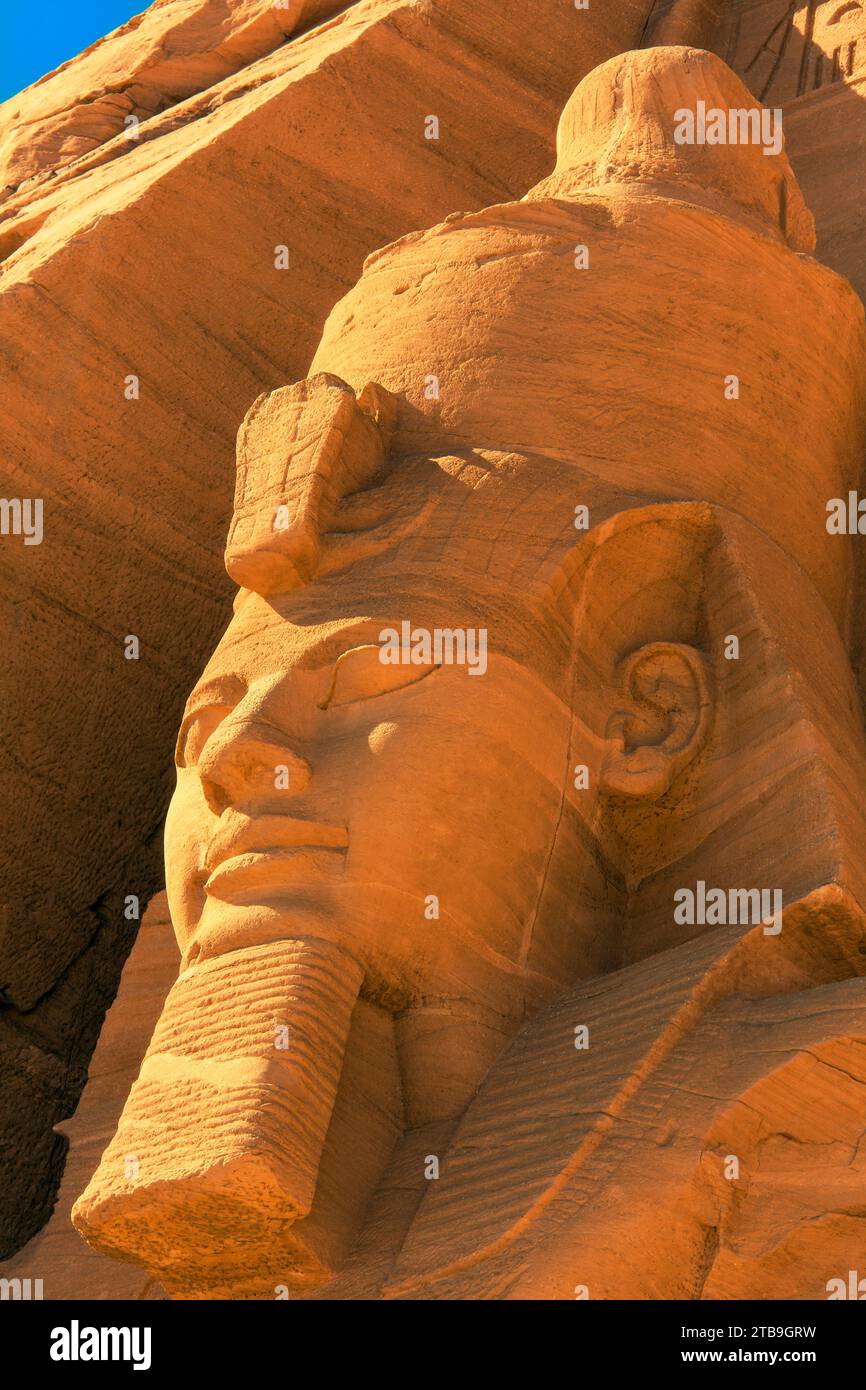 Primo piano della testa di una delle statue di Ramses II scolpite sul fianco della montagna, davanti al Tempio del grande Sole di Abu Simbel Foto Stock