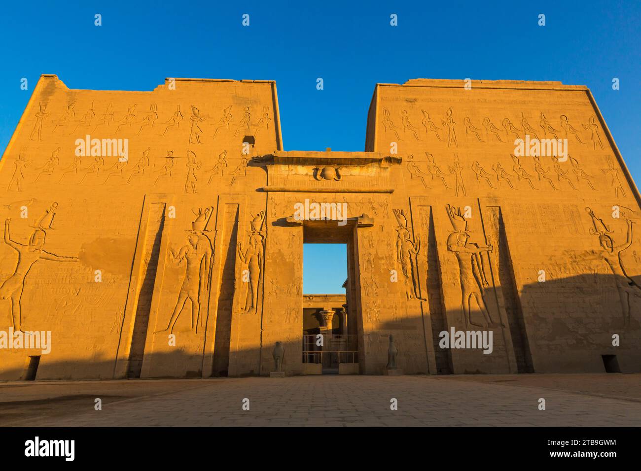 L'imponente pilone d'ingresso del Tempio di Horus con luce dorata e un cielo blu; Edfu, Egitto, Nord Africa Foto Stock