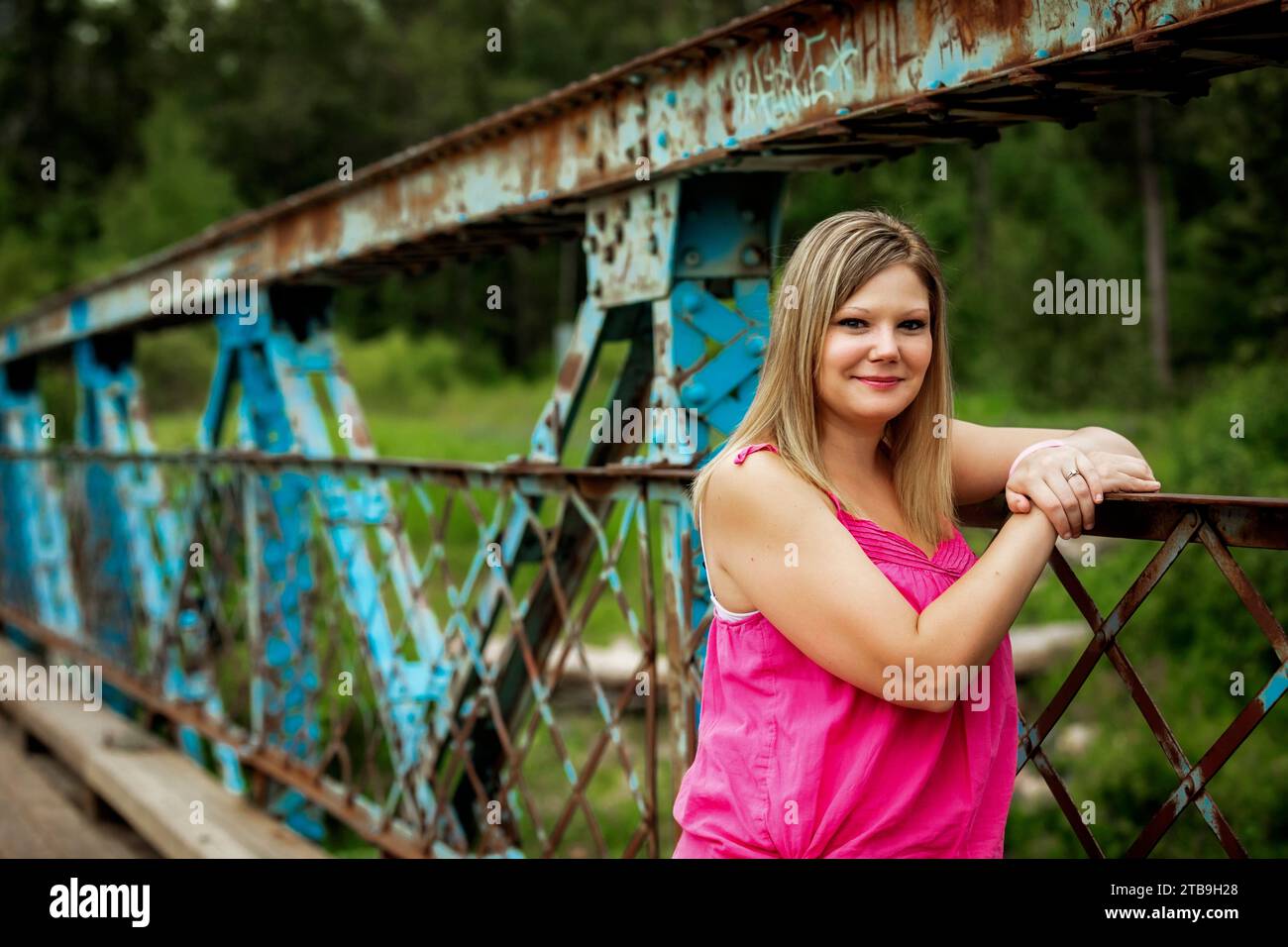 Ritratto ravvicinato di una donna in piedi su un ponte a cavalletto durante una passeggiata nella natura in un parco, in posa per la macchina fotografica; Edmonton, Alberta, Canada Foto Stock