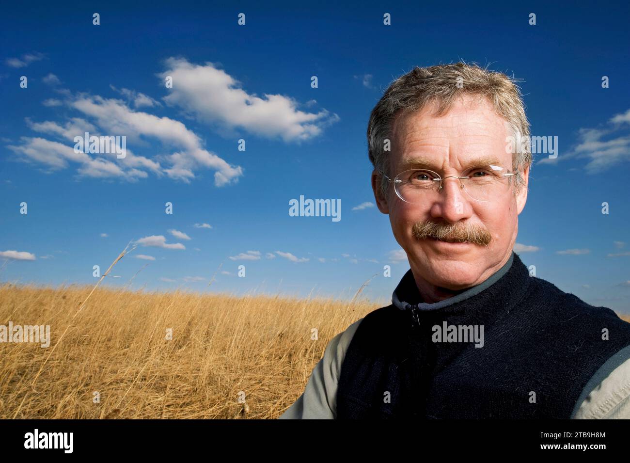 Ritratto all'aperto di un uomo maturo in piedi accanto a un campo d'erba dorata in campagna; Lincoln, Nebraska, Stati Uniti d'America Foto Stock