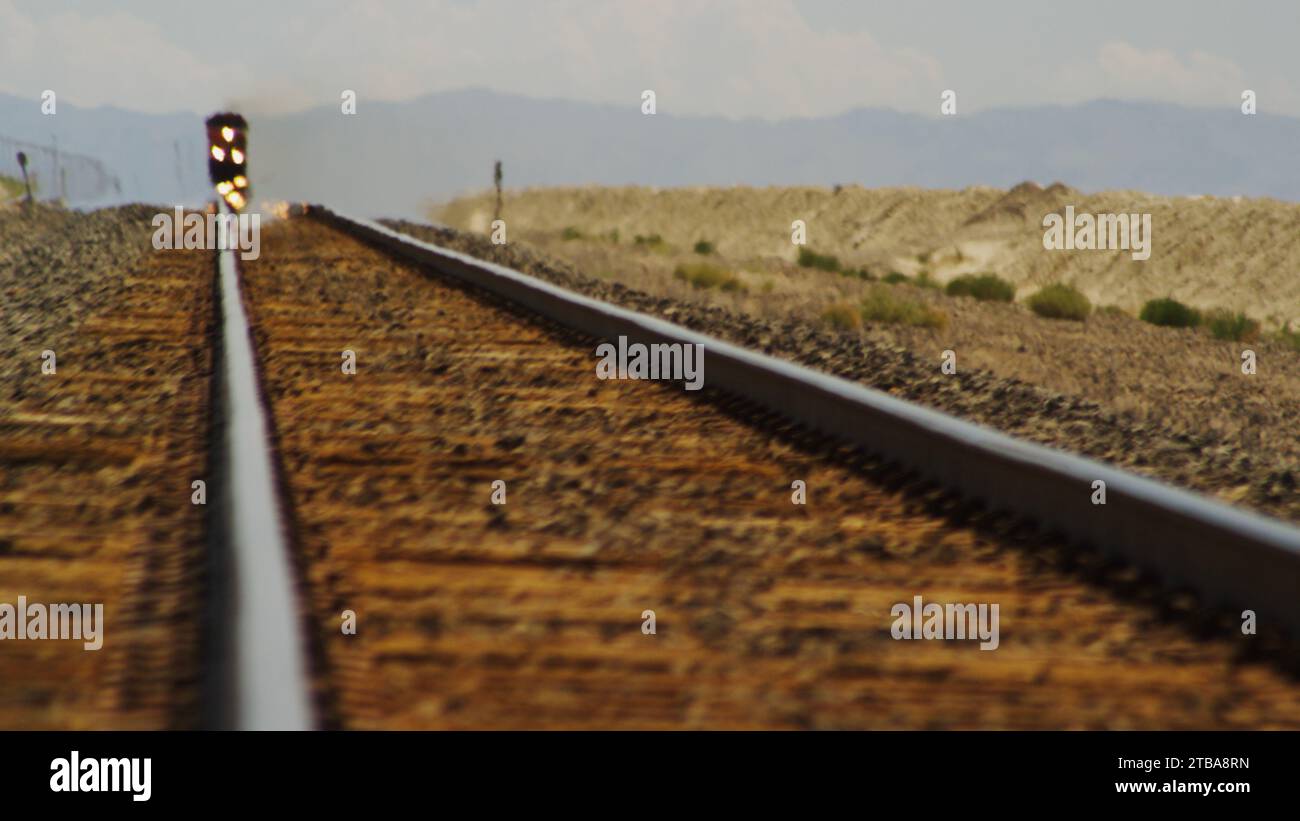 Il treno merci sfreccia attraverso un miraggio nel deserto. Foto Stock