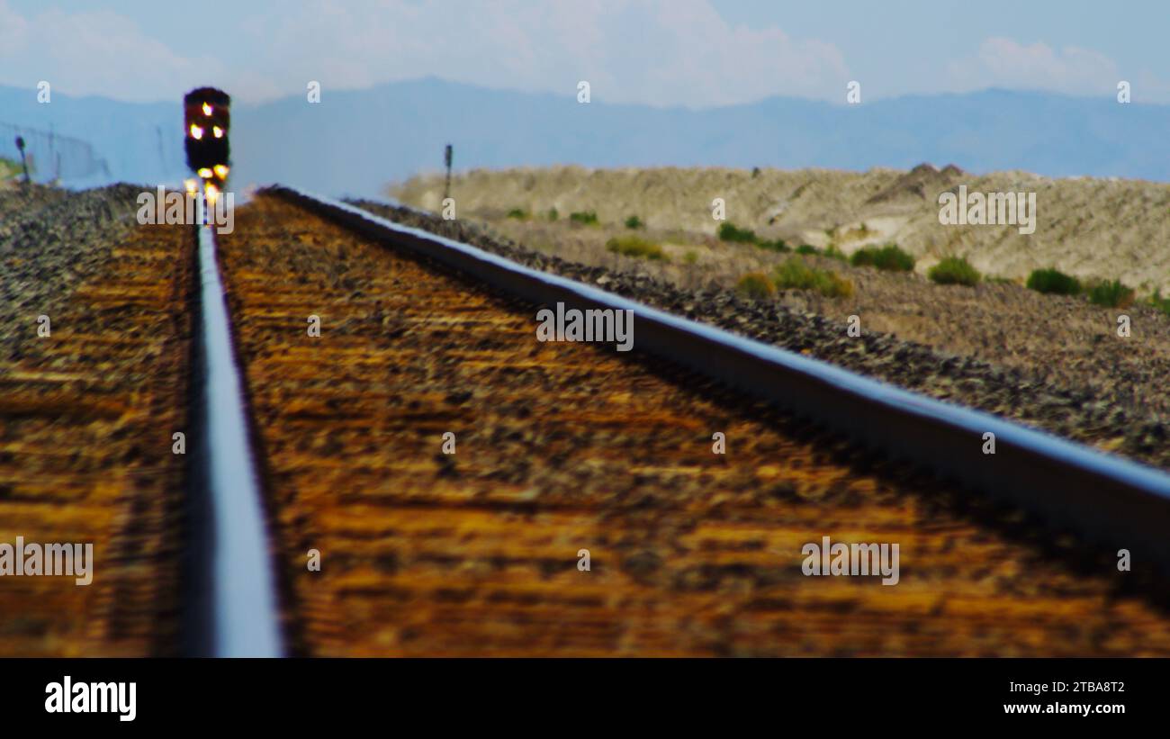 Il treno merci sfreccia attraverso un miraggio nel deserto. Foto Stock