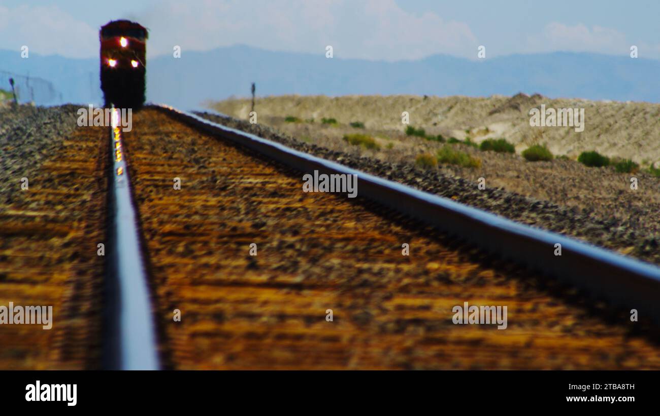 L'avvicinamento dei treni merci passa attraverso un miraggio nel deserto. Foto Stock