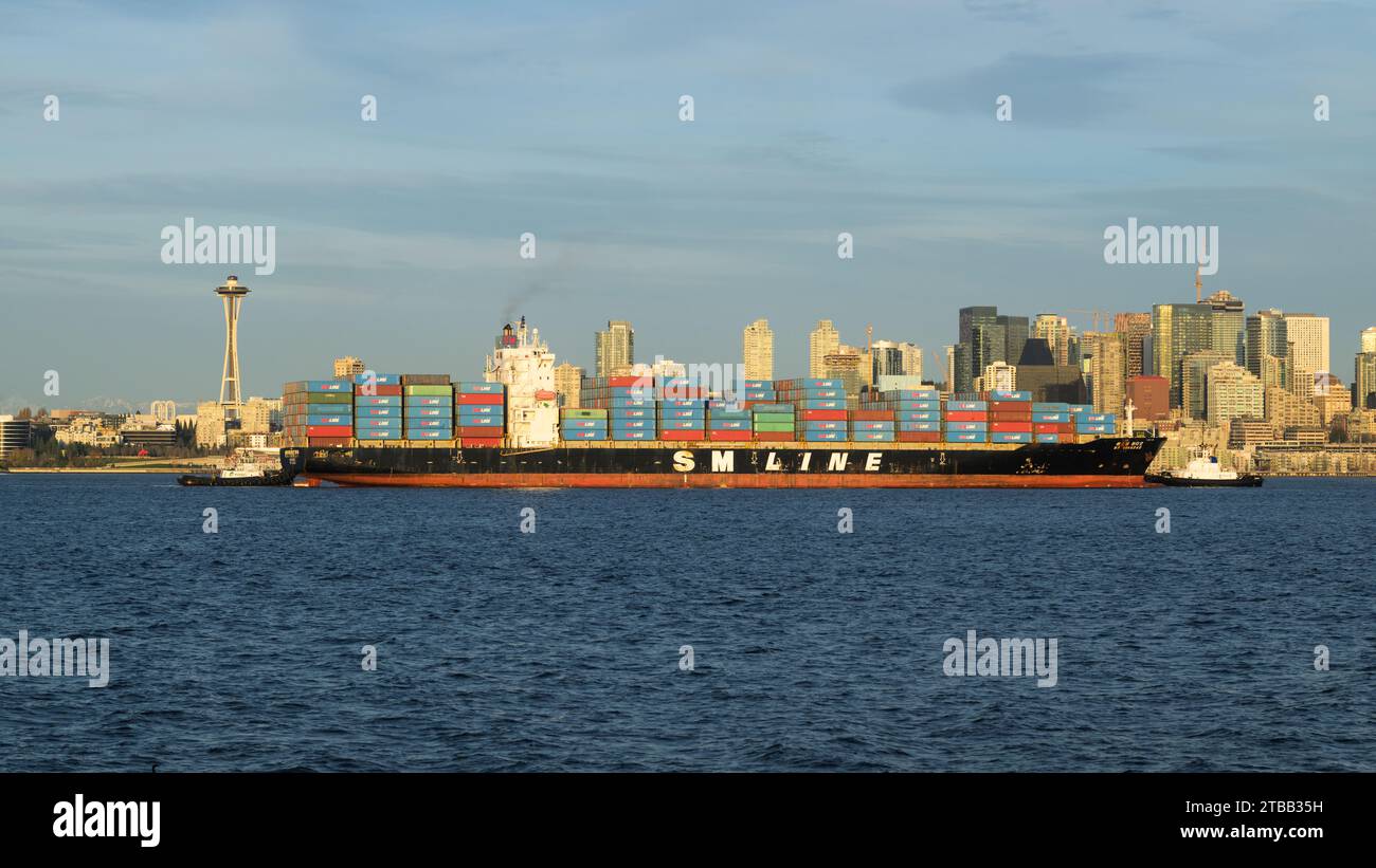 Seattle - 20 novembre 2023; due rimorchiatori guidano la nave container Qingdao della SM Line oltre lo Space Needle di Seattle Foto Stock