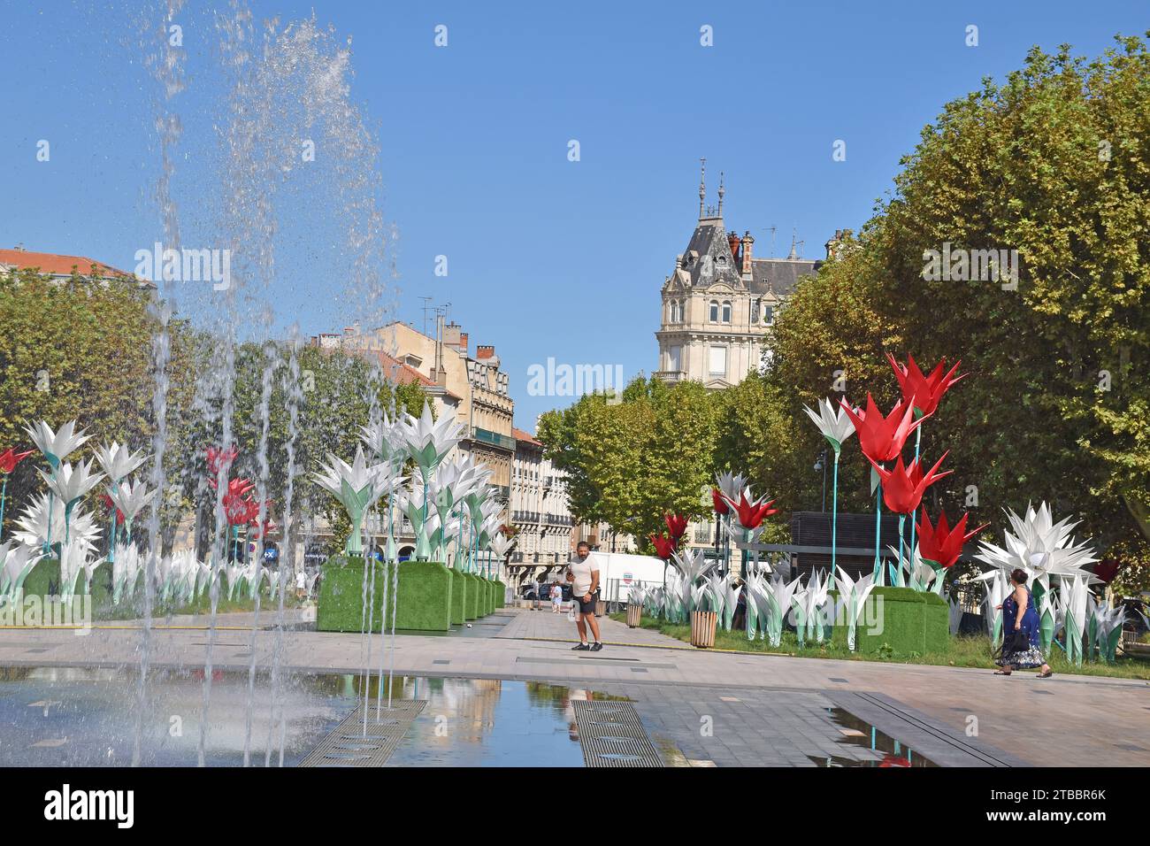 Place Jean Jaures, uno spazio pubblico all'aperto nel centro di Béziers, Francia, con fontane moderne, enormi sculture floreali e stand di alberi di aerei Foto Stock