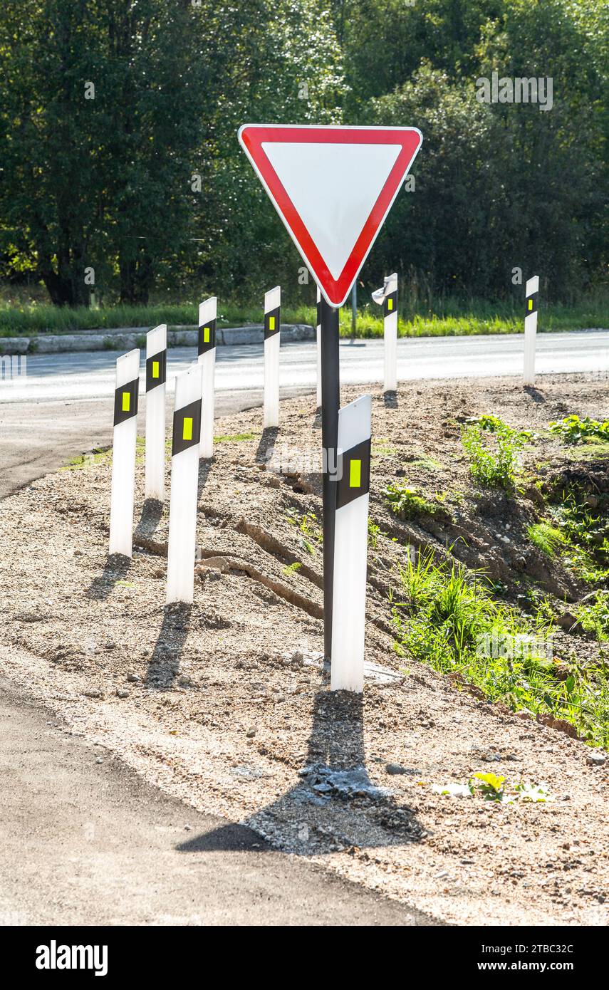 Segnaletica stradale "Give Way" quando si esce da una strada secondaria per la strada principale. Lascia spazio al traffico sulla strada principale. Esci dalla strada secondaria verso la strada principale Foto Stock