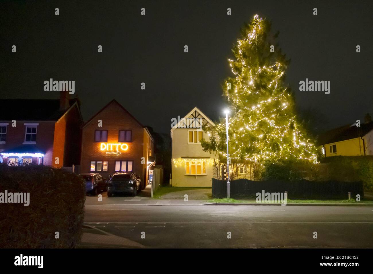 Una casa con un enorme albero di Natale illuminato e una casa con DITTO e una freccia che indica l'altra. Foto Stock