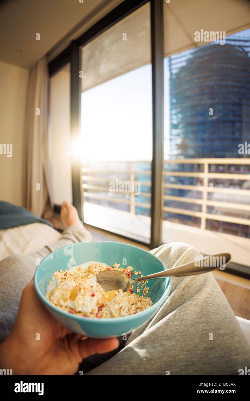 Mangiare una ciotola di cereali in un appartamento cittadino Foto Stock