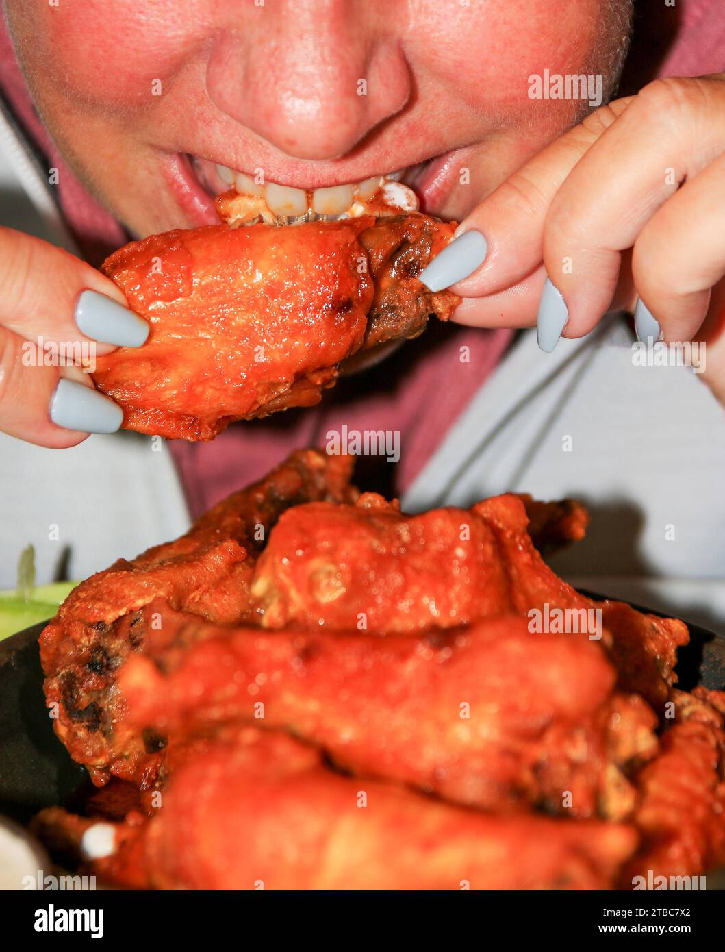 Un primo piano di una persona che mangia ali di pollo al bufalo. Foto Stock