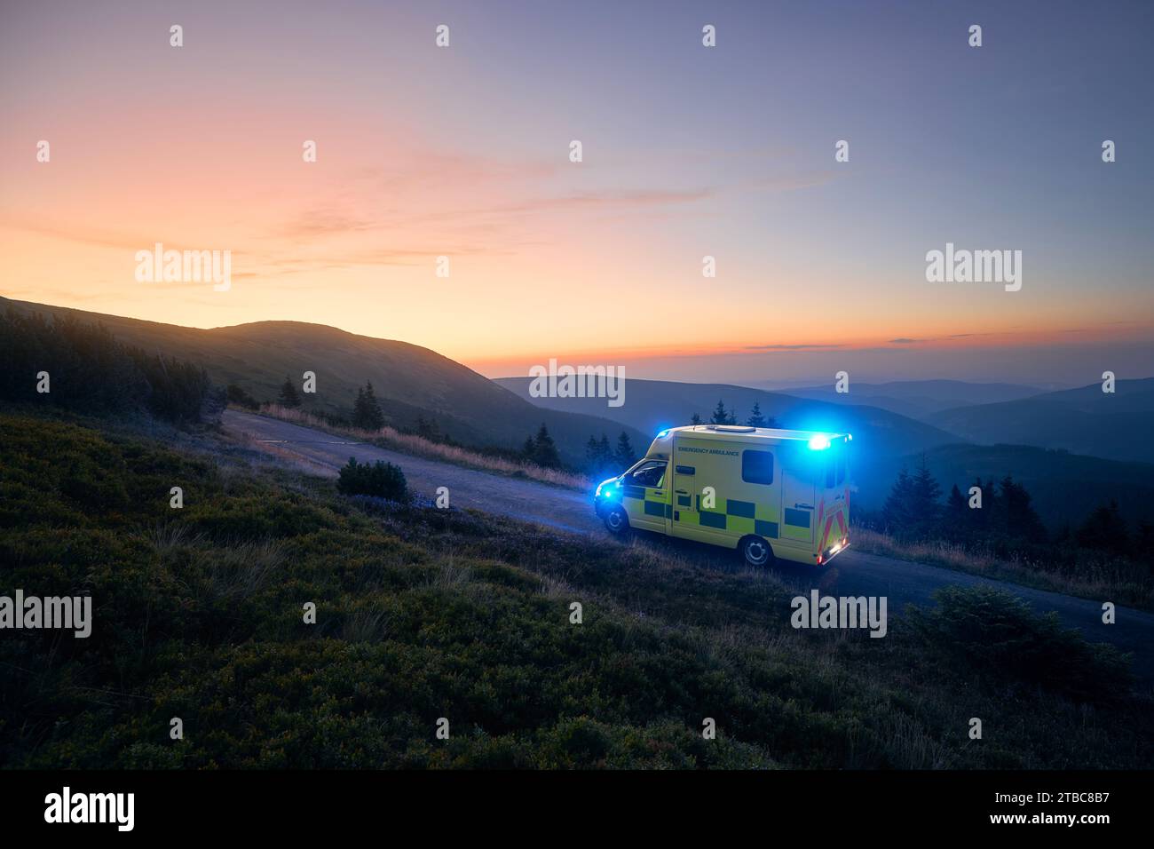 Ambulanza auto di servizio medico di emergenza strada di montagna contro l'alba. Moody Sky con spazio per le copie. Temi salvataggio, urgenza e assistenza sanitaria. Foto Stock