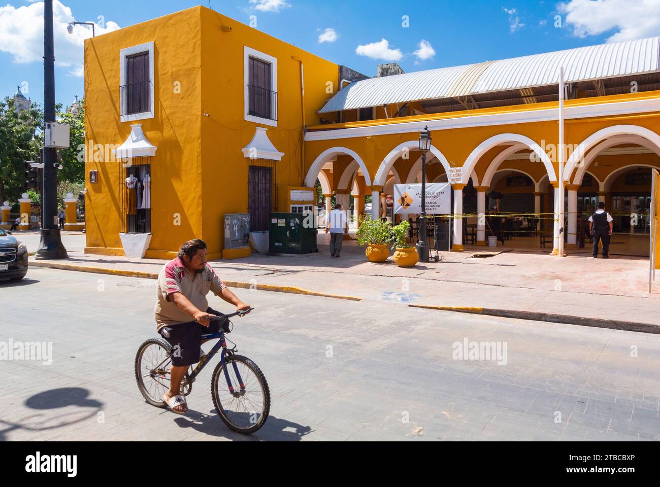 Valladolid, Yucatan, Messico, uomo locale in bicicletta di fronte al Mercado De Comida con architettura coloriale, solo editoriale. Foto Stock
