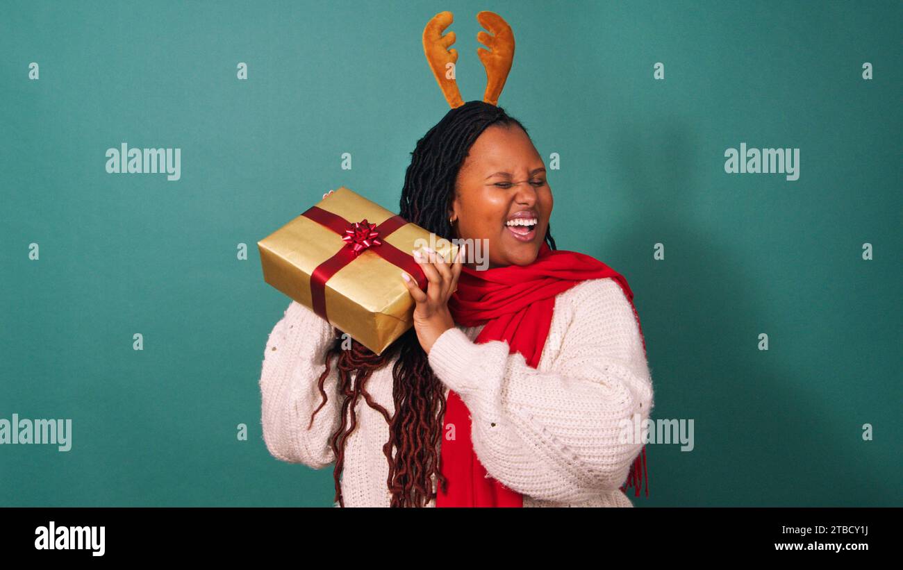 La bella donna nera scuote la danza del regalo di Natale, eccitata per il regalo, studio Foto Stock