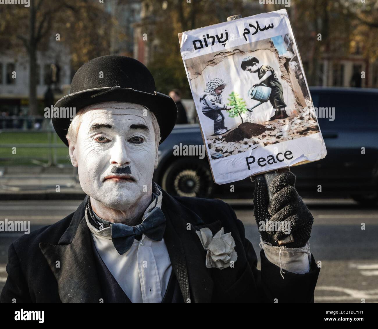 Londra, Regno Unito. 6 dicembre 2023. Un manifestante vestito da Charles Chaplin, che trasmette un messaggio di "pace" riguardo al conflitto israelo-Hamas, sta bloccando i cancelli d'ingresso principali delle camere del Parlamento di Westminster con il suo scooter di mobilità. Il manifestante ha problemi di linguaggio e mobilità, e sembra pacifico, ma si rifiuta di muoversi dai cancelli e alla fine viene arrestato e scrupolosamente spostato in un veicolo speciale della polizia con una rampa. Crediti: Imageplotter/Alamy Live News Foto Stock