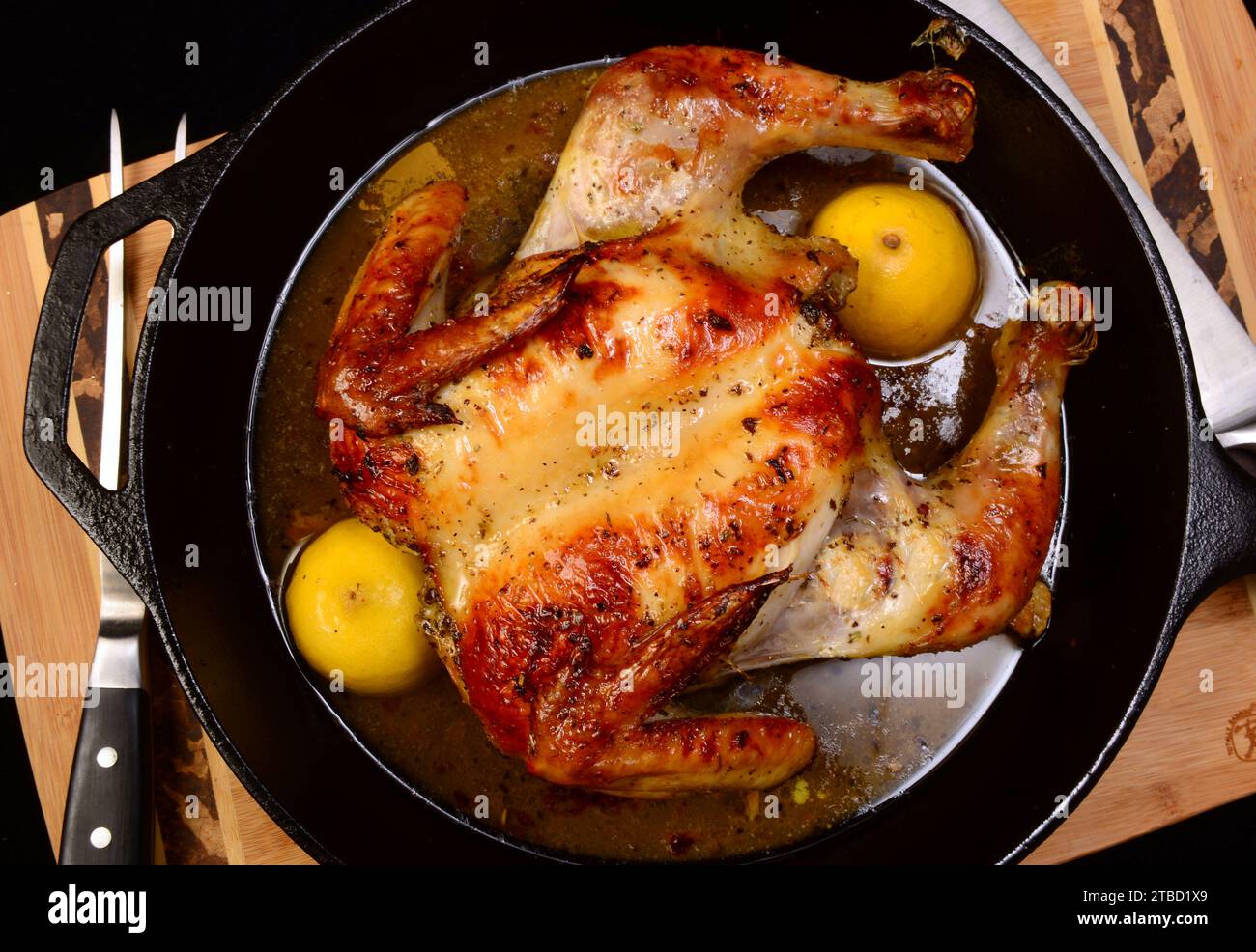 Pollo intero che è stato spatchcocked arrostito in una padella di ghisa con limone, olio d'oliva e salsa di origano. Foto Stock