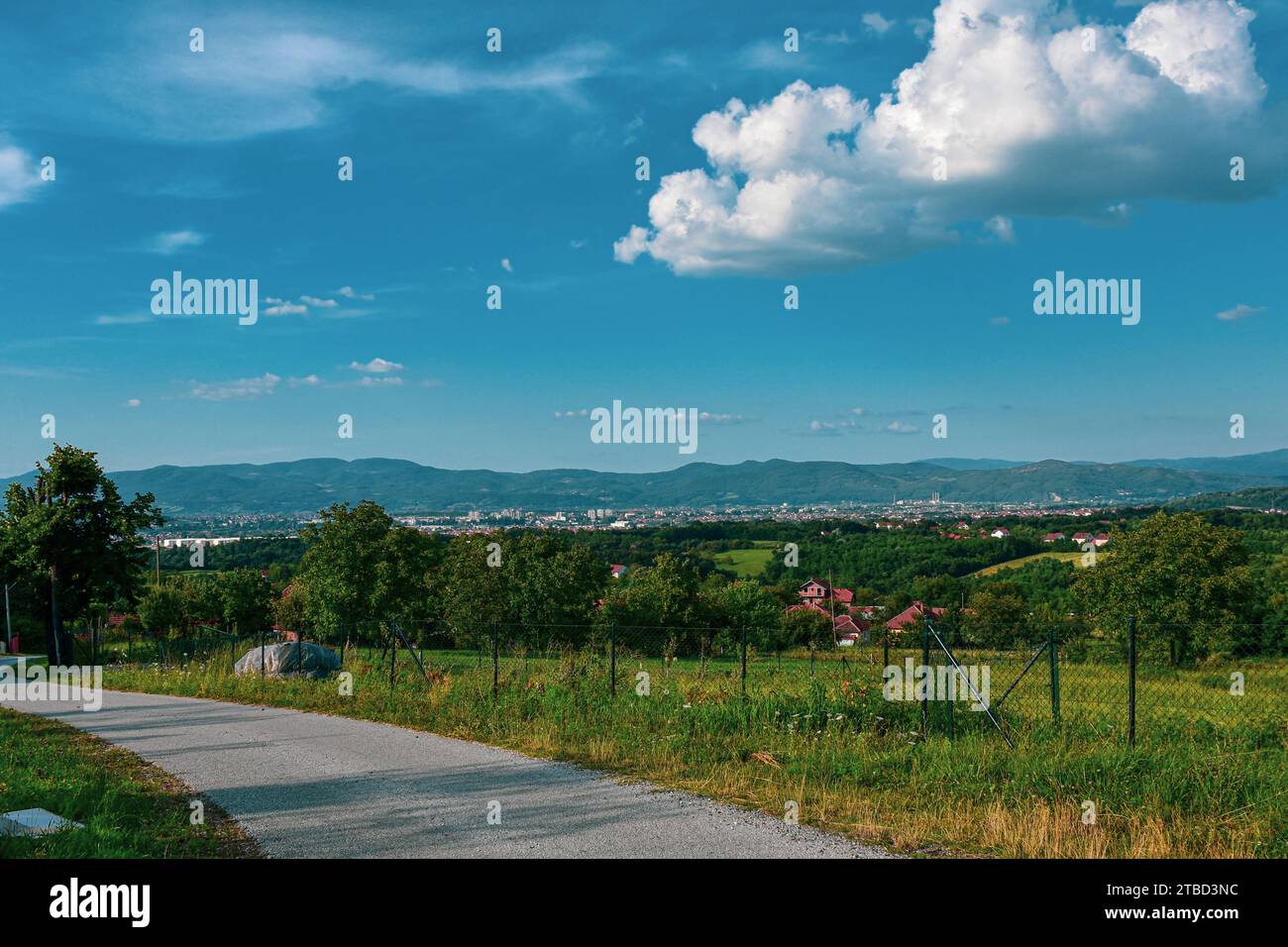 La strada di campagna si snoda sopra il villaggio con vista sull'insediamento rurale e urbano Foto Stock