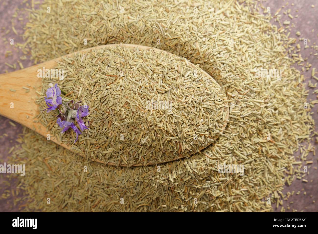 Cucchiaio di legno con rosmarino essiccato macinato su una pila di semi e un fiore di rosmarino fresco appena tagliato Foto Stock