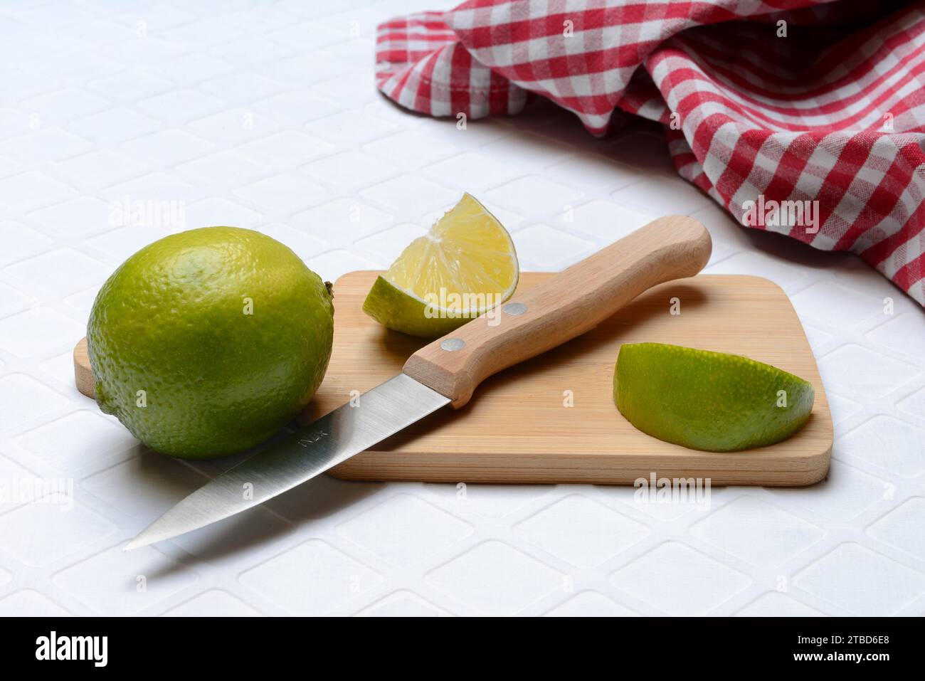 Affettare i limi su un tagliere con un coltello da cucina Foto Stock