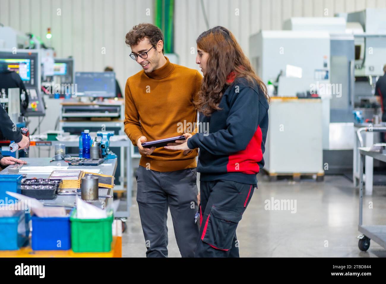 Manager maschio e dipendente donna che lavora con tablet in una fabbrica cnc Foto Stock