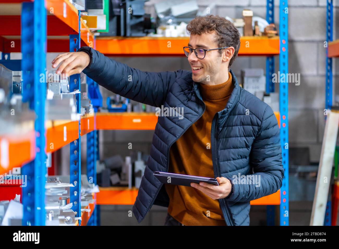 Orgoglioso ingegnere nel magazzino di una fabbrica cnc che utilizza tablet e sorride Foto Stock