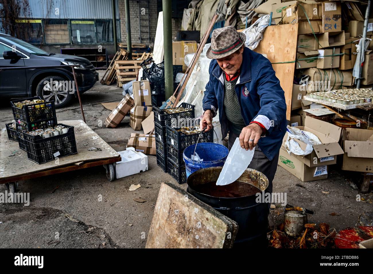 ZAPORIZHZHIA, UCRAINA - 5 DICEMBRE 2023 - il volontario di 79 anni conosciuto come zio Fedir aggiunge uno schiaffo di paraffina in una botte mentre fa Foto Stock