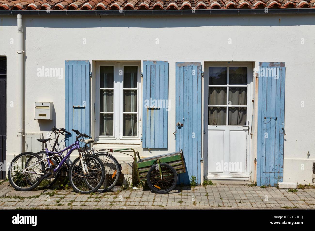 Vecchia casa con persiane, finestre, porta e biciclette con rimorchio sull'isola di Ile-d'Aix, Charente-Maritime, Francia Foto Stock