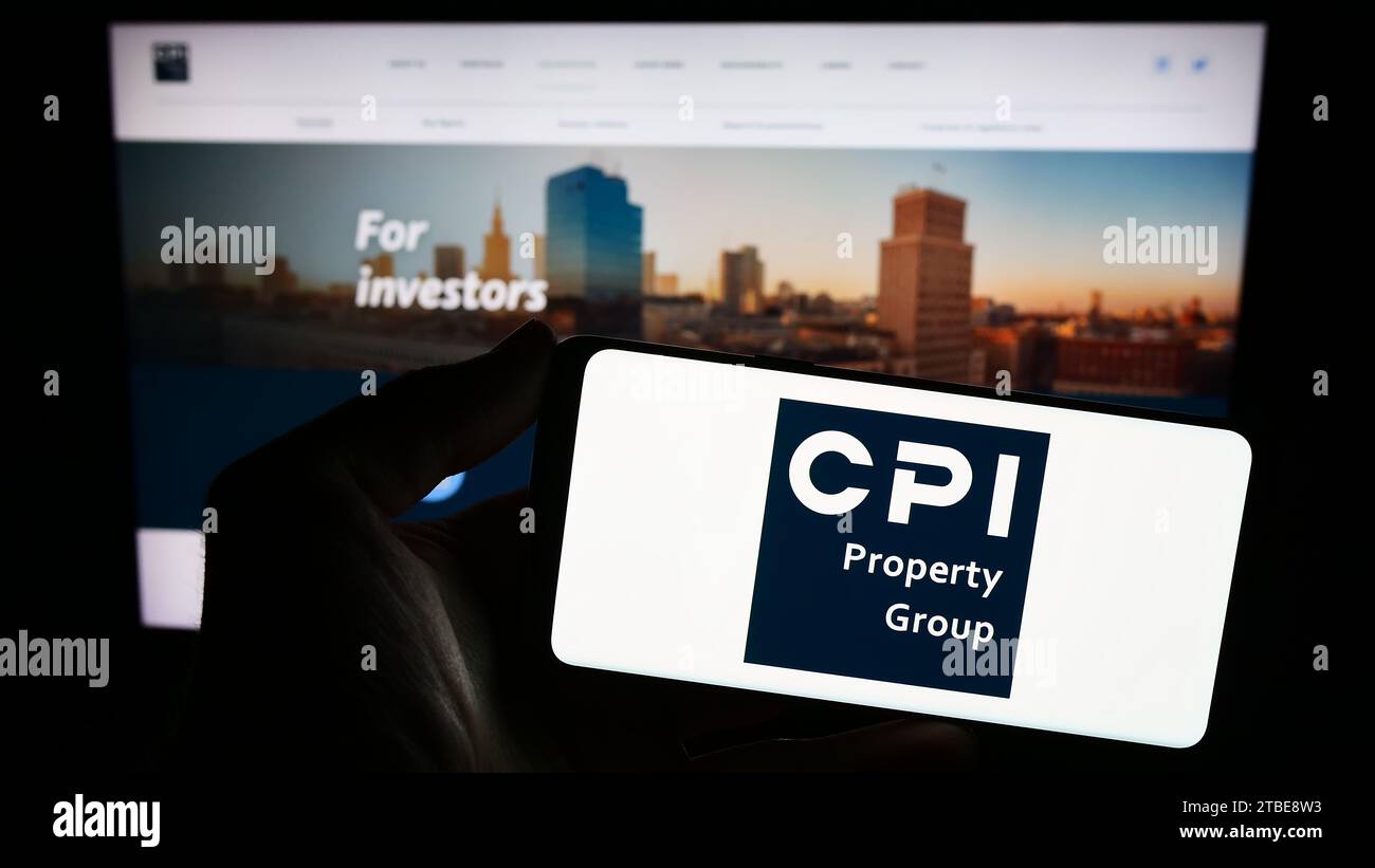 Persona che possiede un telefono cellulare con il logo della società immobiliare CPI Property Group (CPIPG) davanti alla pagina Web aziendale. Concentrarsi sul display del telefono. Foto Stock