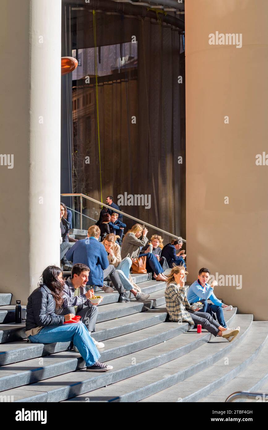 Giovani felici seduti (lavoratori d'ufficio) al sole di mezzogiorno d'inverno sui gradini dell'8 Chifley Square, grattacielo di Sydney in Australia Foto Stock