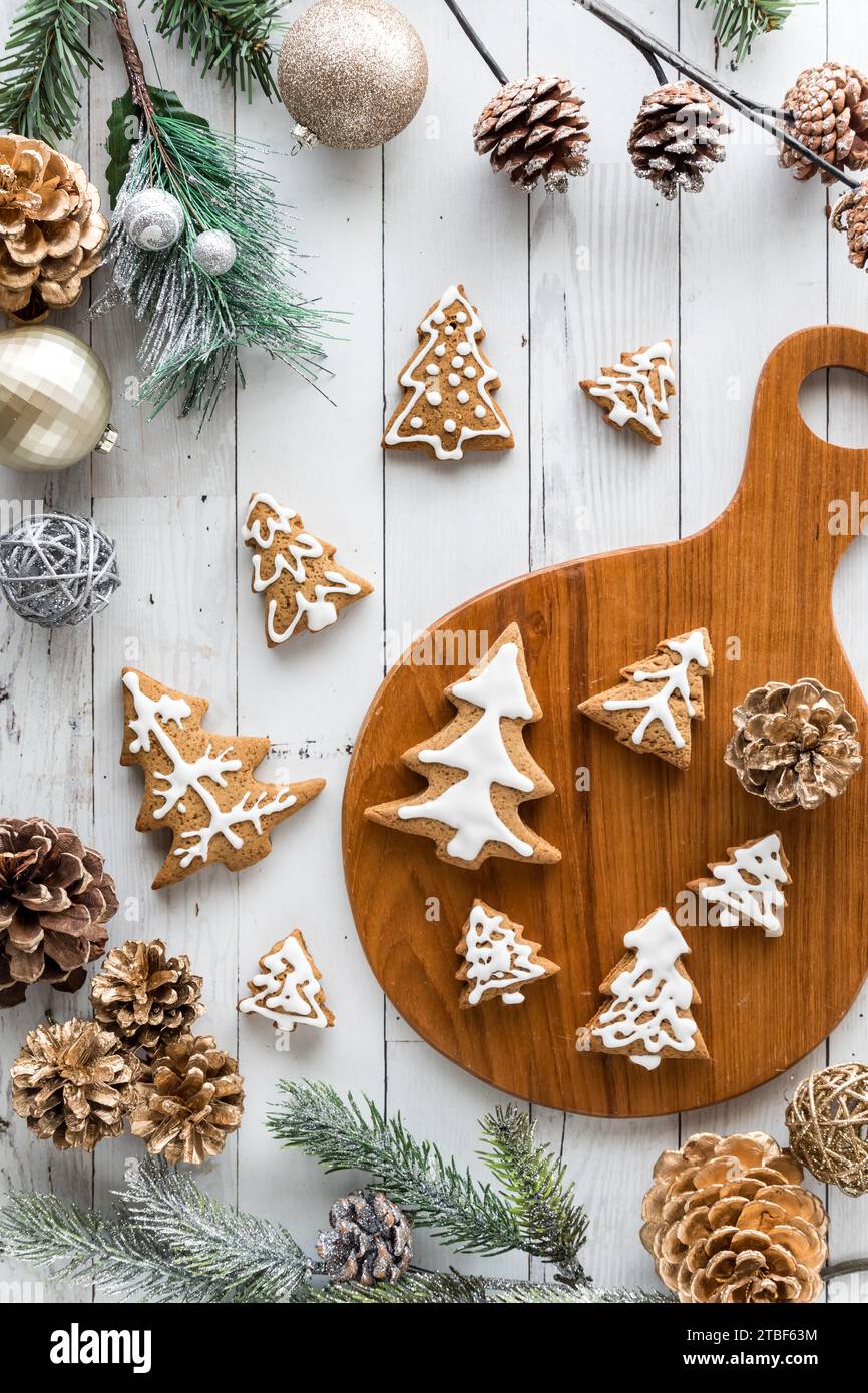Un assortimento di biscotti a forma di albero di vacanza circondati da decorazioni natalizie. Foto Stock