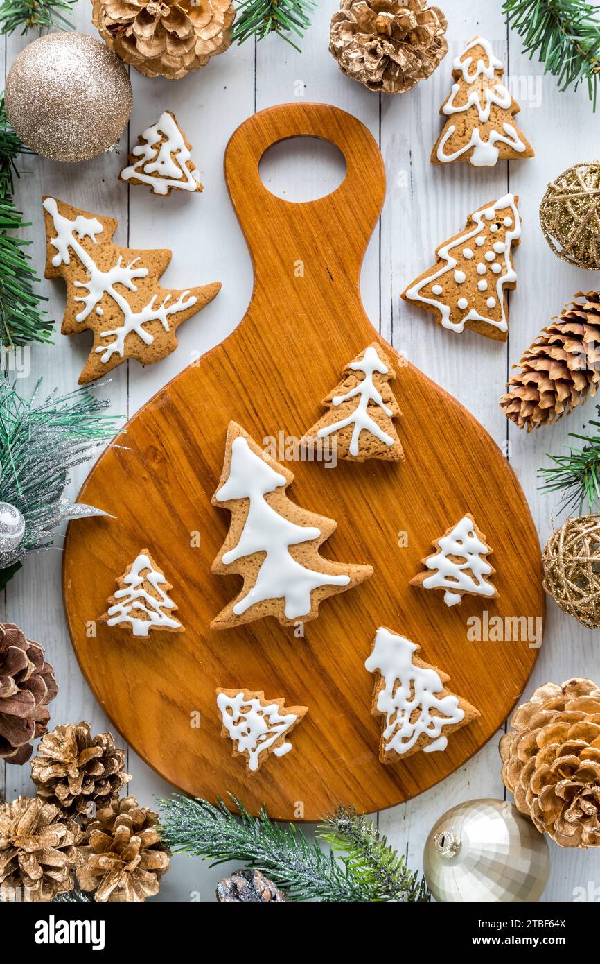 Biscotti al pan di zenzero decorati con alberi di vacanza circondati da decorazioni festive. Foto Stock