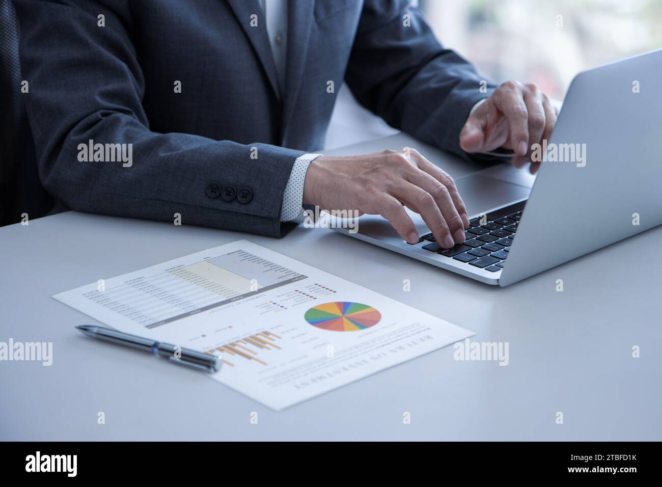 Uomo d'affari che lavora con un computer portatile mentre esamina le prestazioni aziendali e il ritorno sugli investimenti Foto Stock