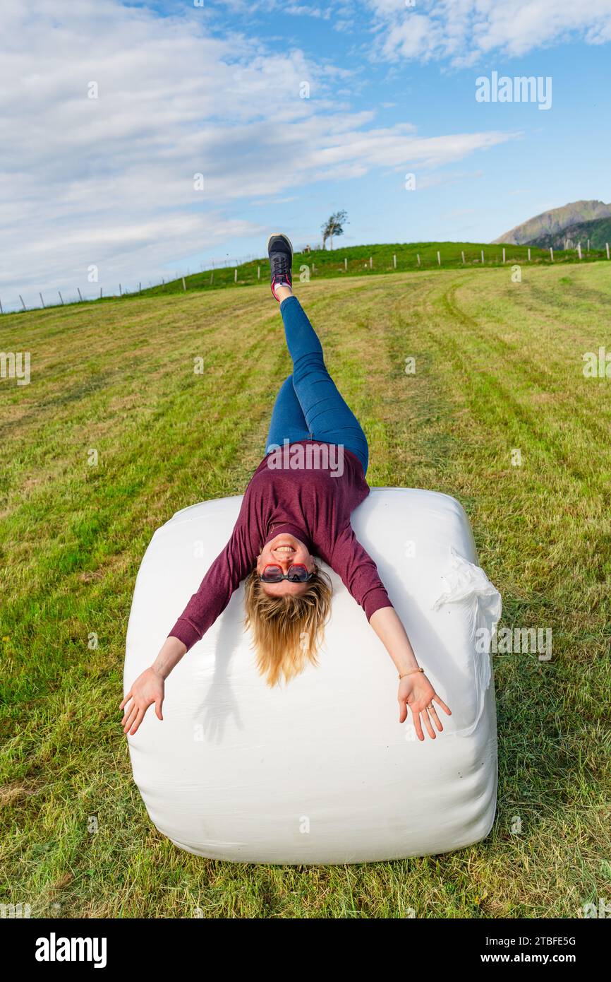 Bella donna di 40 anni che posa su una pila piena di fieno in un ambiente tranquillo Foto Stock