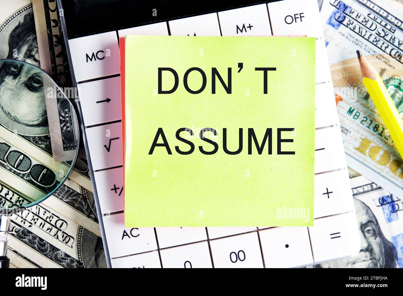 NON ASSUMERE testo, una parola scritta su un adesivo che giace su una calcolatrice su uno sfondo di denaro Foto Stock