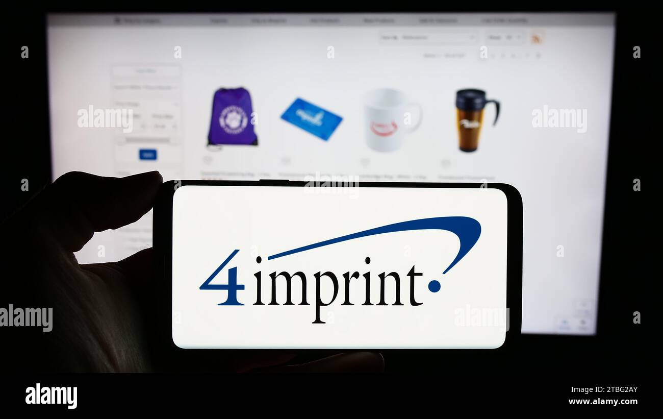Persona che possiede un cellulare con il logo della società di merchandising promozionale 4imprint Group plc davanti alla pagina Web aziendale. Concentrarsi sul display del telefono. Foto Stock