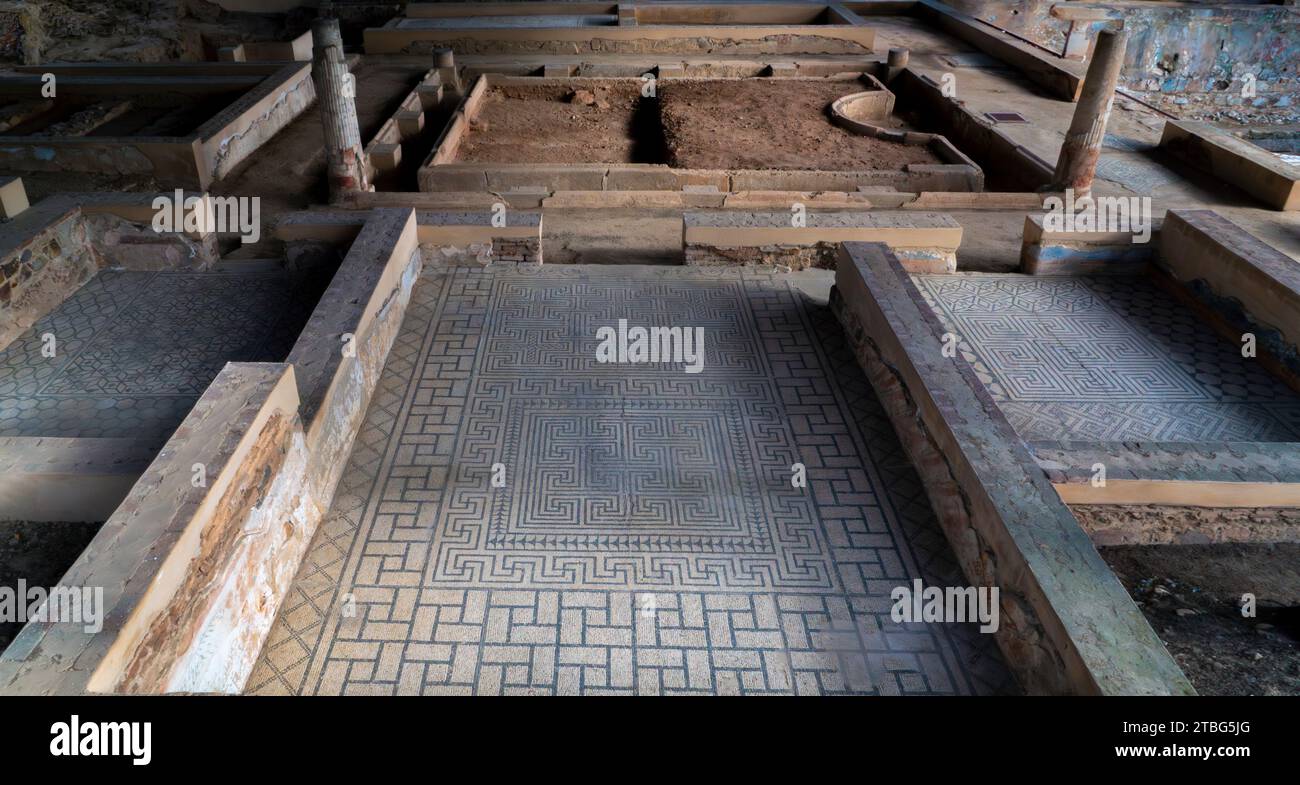 Resti delle rovine archeologiche di un mosaico romano sul pavimento di una sala con figure geometriche blu che creano una struttura frattale nel Mitreo Foto Stock
