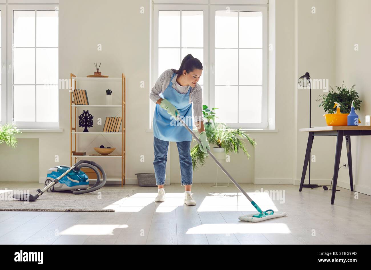La donna si dedica alla pulizia dei pavimenti con uno spazzolone Foto Stock