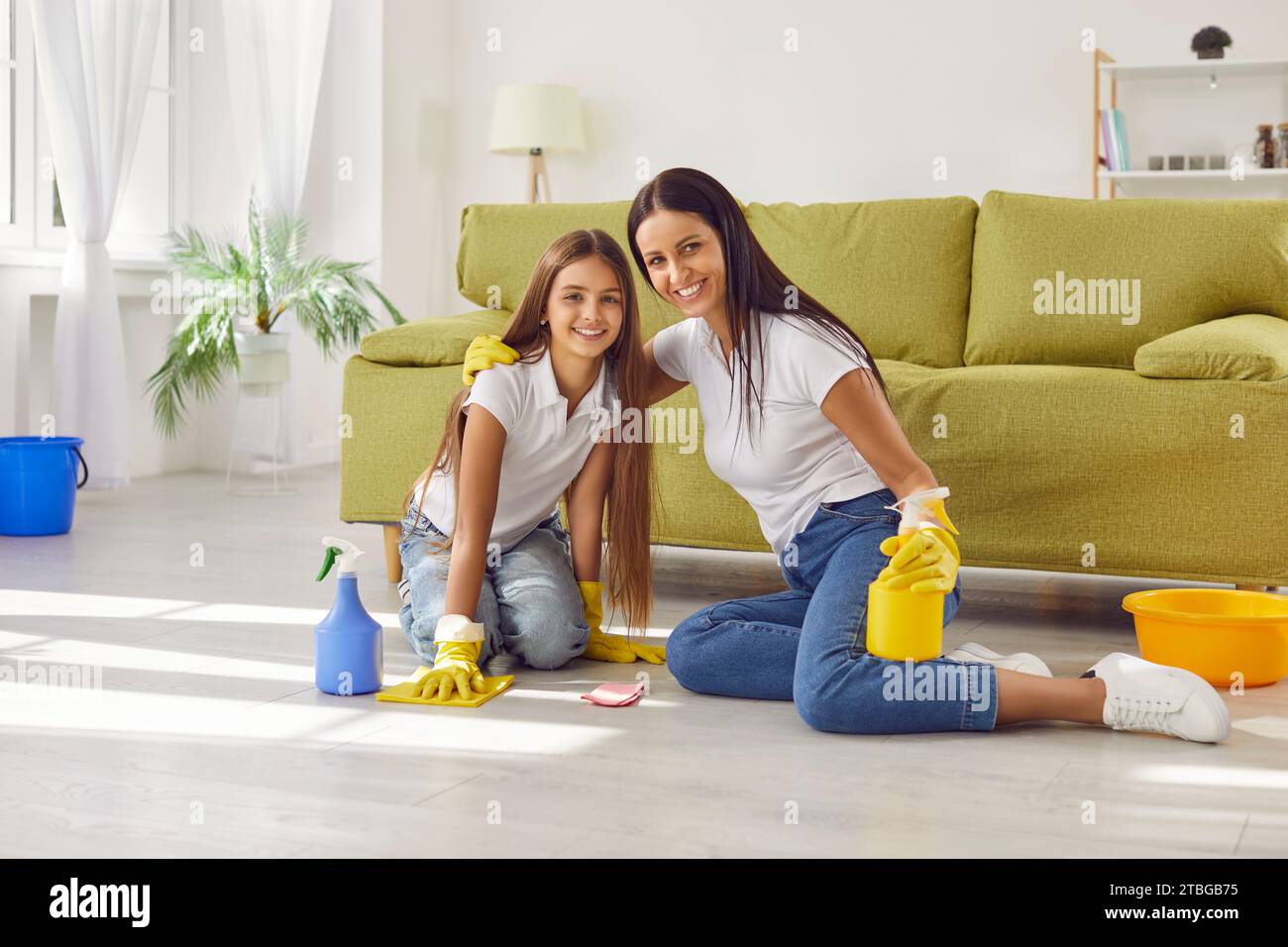 Felice e sorridente madre con una figlia che lavava il pavimento nel soggiorno di casa. Foto Stock