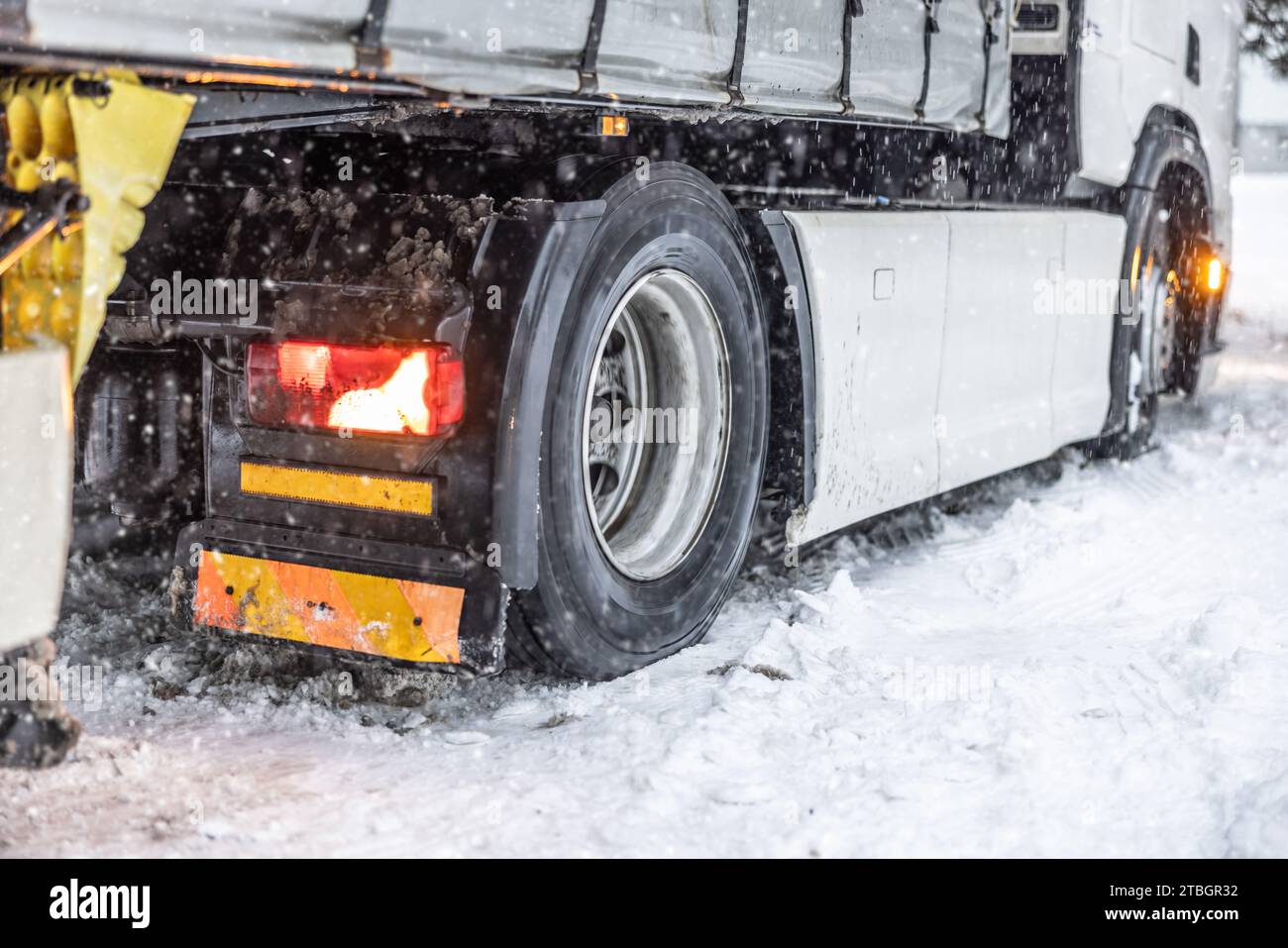 Le ruote del camion scivolano su una strada innevata e ghiacciata. Foto Stock