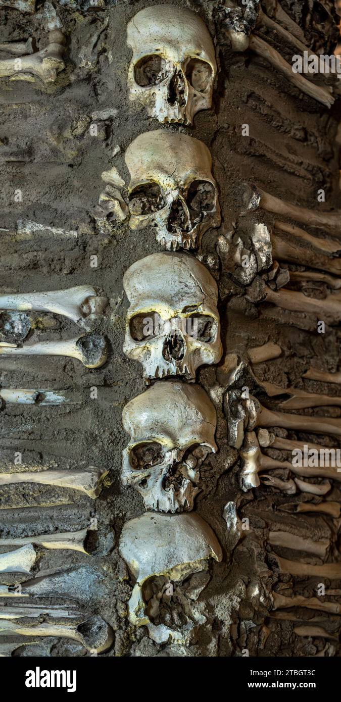 Cinque teschi umani uno sopra l'altro con ossa ai lati che creano un disegno macabro della Cappella delle ossa situata nella città di Évora in Portug Foto Stock