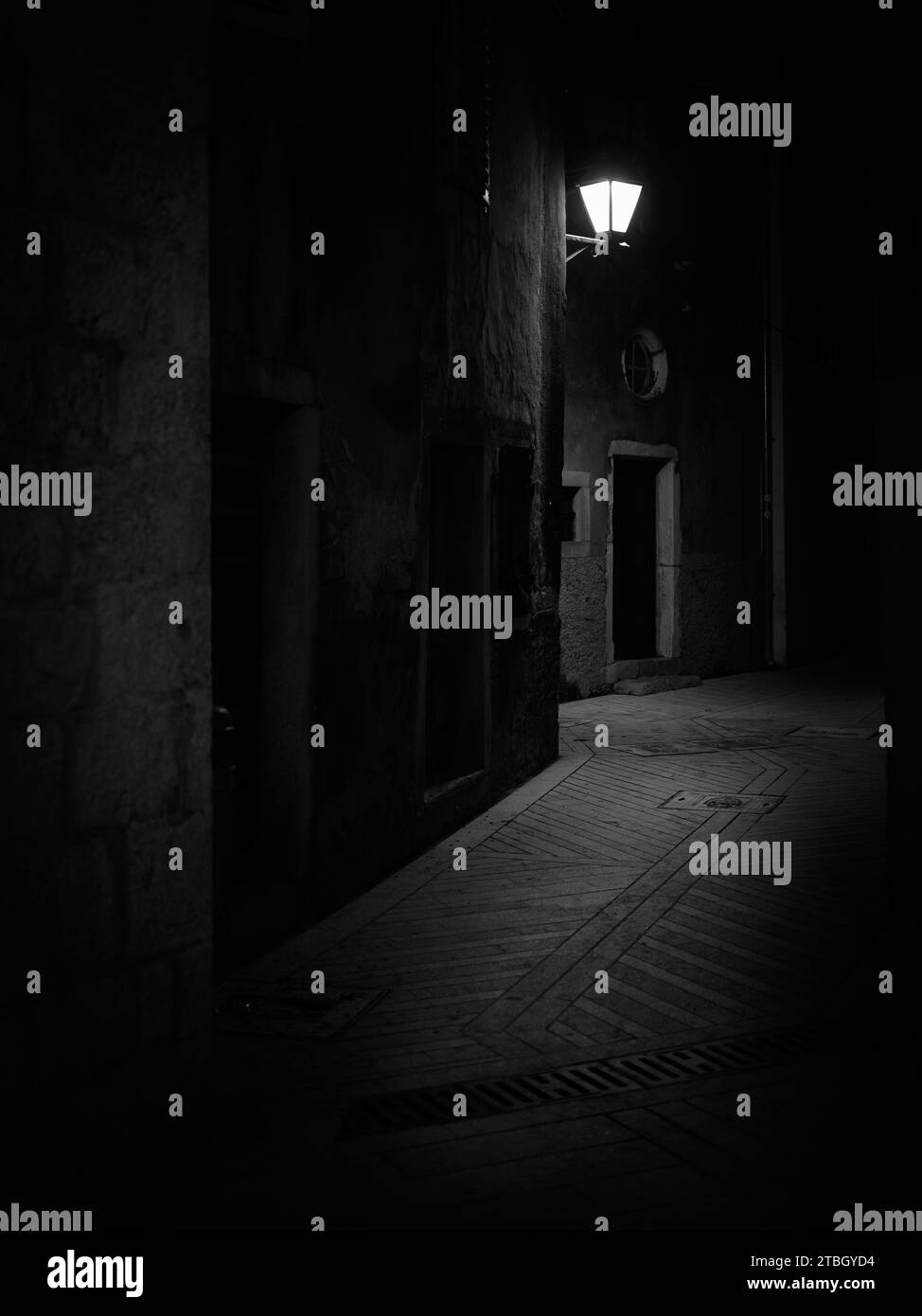Cherso, Croazia - 23 ottobre 2022: Strada stretta a Cherso con vecchi lampioni di notte, bianco e nero Foto Stock