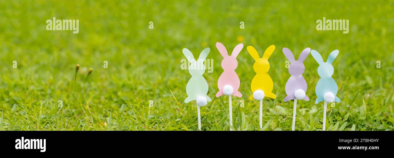 Su uno sfondo azzurro, i coniglietti pasquali tagliano carta colorata, forbici, pennarelli. Concetto di Pasqua, artigianato per bambini, applique. FLA Foto Stock