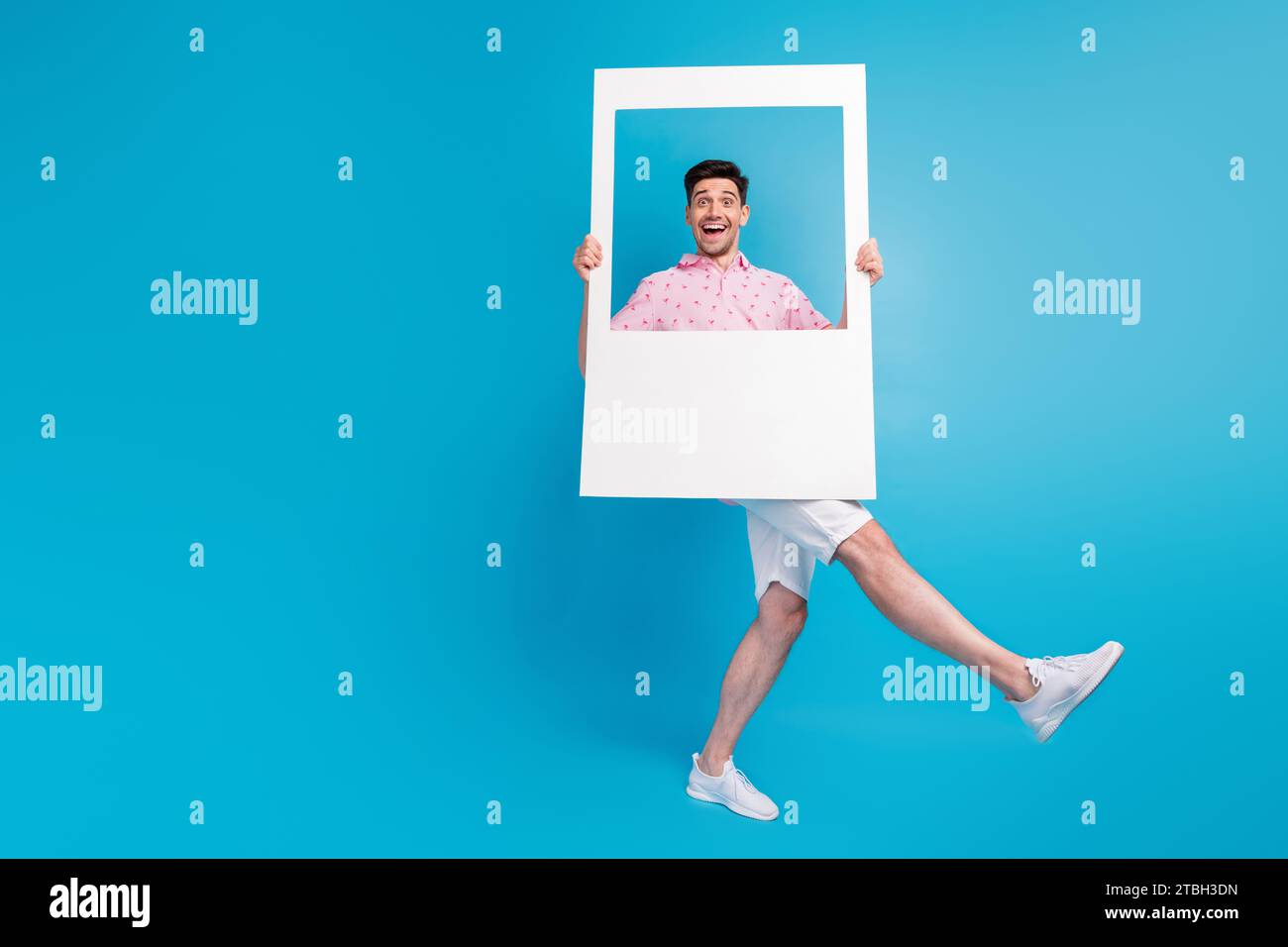 Foto a grandezza naturale di una persona allegra e felice che tiene un album di carta che balla isolato su sfondo blu Foto Stock
