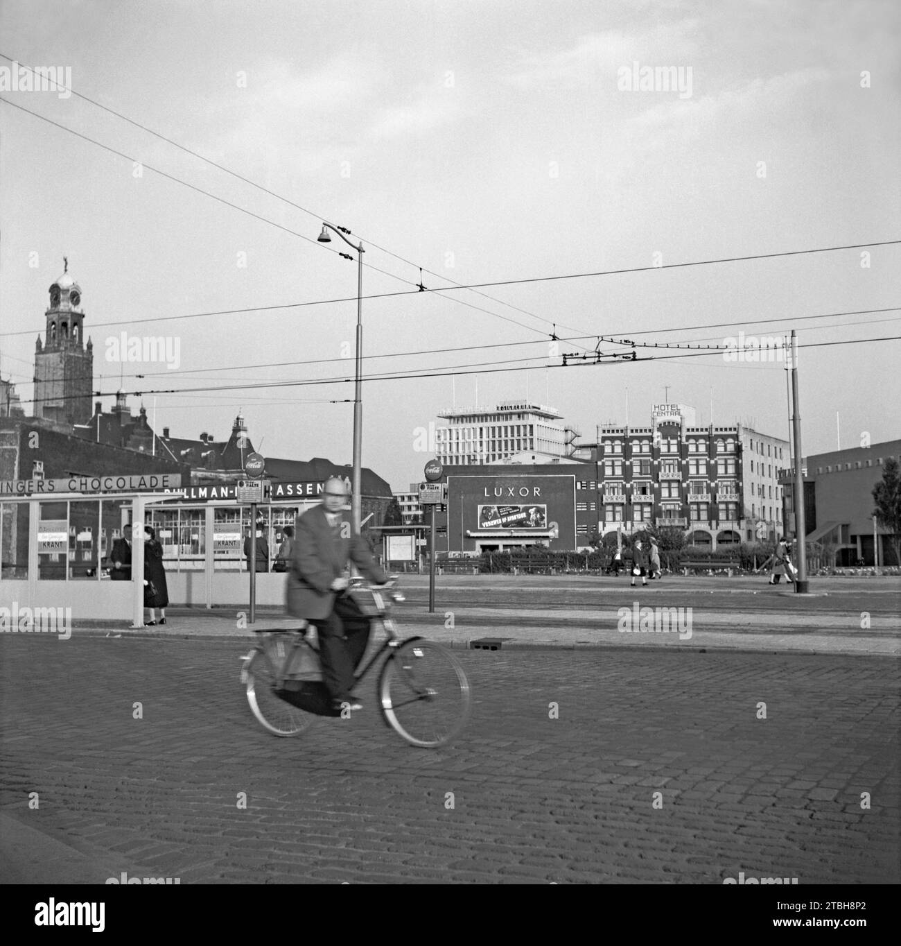 Una vista di Rotterdam nel 1955: È stata fotografata guardando a sud dalla fermata del tram di Weena mentre un ciclista passava. In lontananza si trova il teatro Old Luxor su Kruiskade - spettacolo era "Vrouwen op Avontuur" con Georges Marchal e Maria Mauban. Accanto all'hotel si trova l'Hotel Centraal. Sulla sinistra si trova lo Stadhuis Rotterdam e la sua caratteristica torre dell'orologio. L'edificio moderno è Holbeinhuis. La vista è ora passata con edifici alti e moderni costruiti lungo Weena, una fotografia d'epoca degli anni '1950. Foto Stock