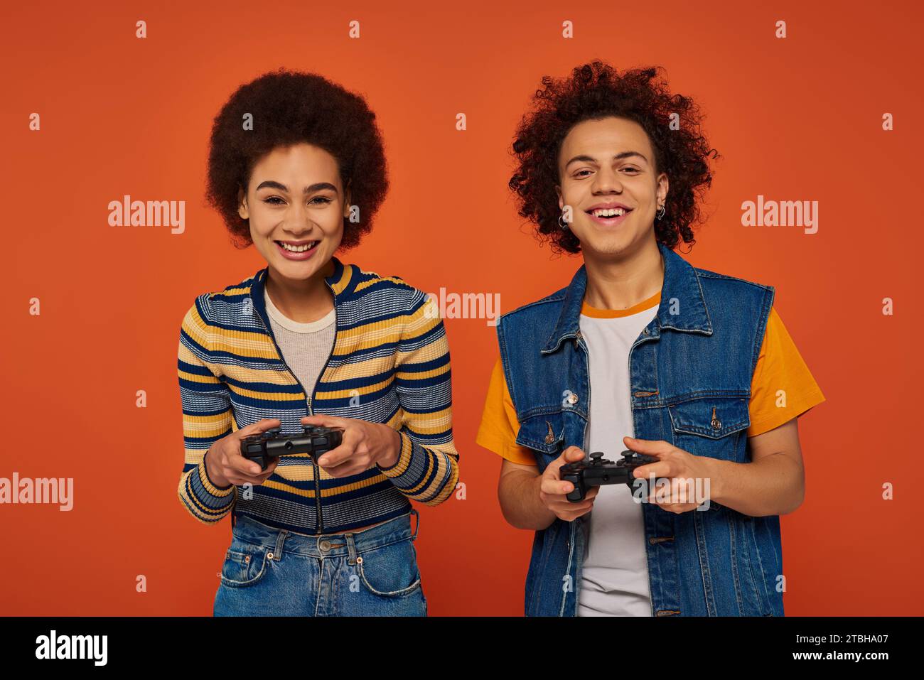 fratello e sorella afro-americani dall'aspetto gradevole che giocano ai videogiochi con joystick, concetto familiare Foto Stock