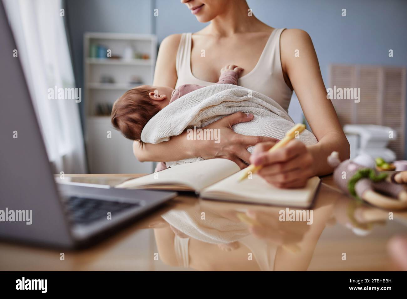Mamma che lavora Lulling Baby durante l'orario di lavoro Foto Stock
