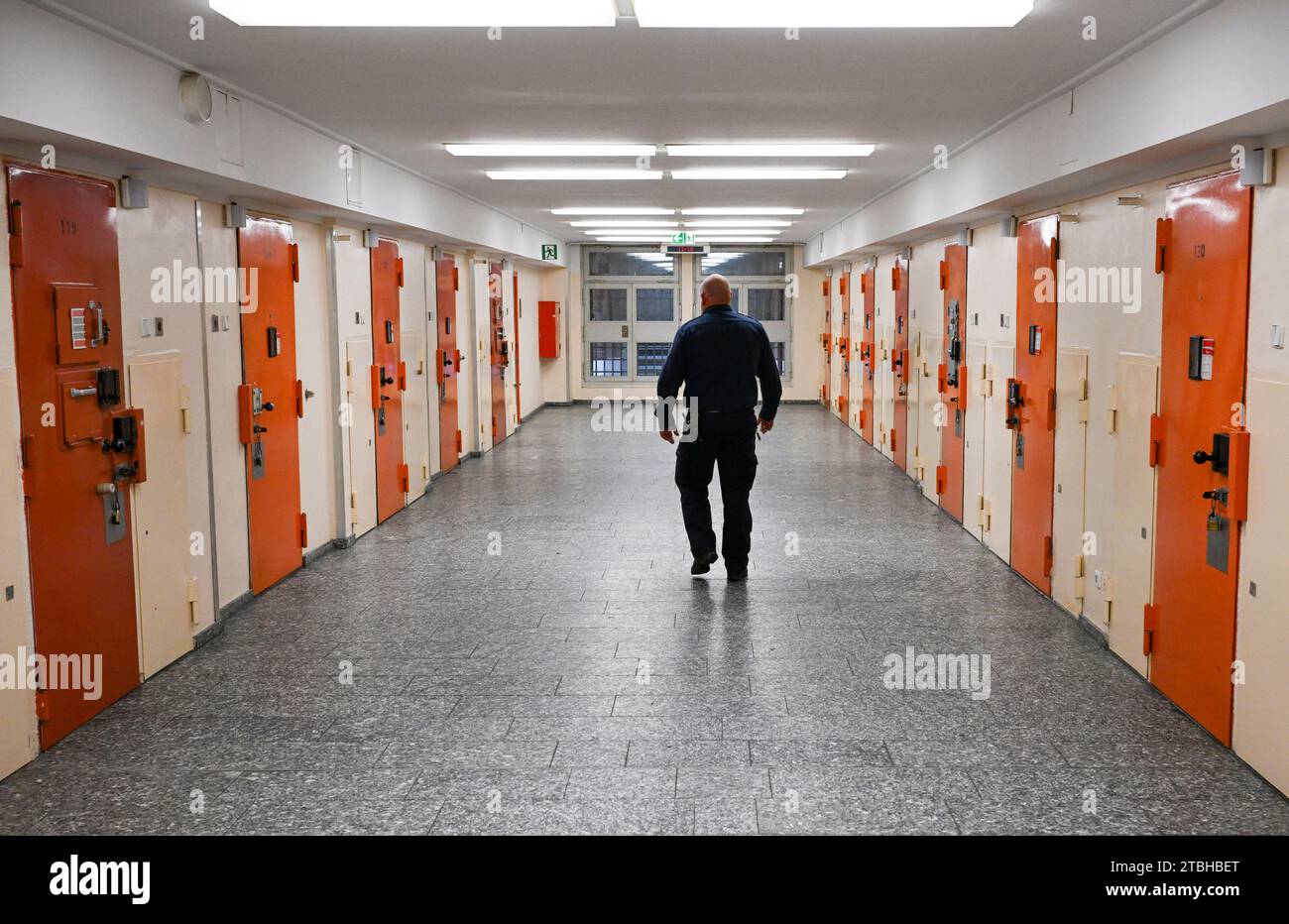 Berlino, Germania. 7 dicembre 2023. Un ufficiale della prigione passa davanti alle porte delle celle nel dipartimento di accesso della prigione di Moabit durante la presentazione dei piani per una stanza di prevenzione del suicidio. (Al dpa "Justice plans more Prevention Against suicide in Prison") credito: Jens Kalaene/dpa/Alamy Live News Foto Stock